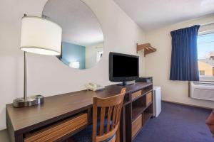 a room with a desk with a television and a mirror at Super 8 by Wyndham College Station in College Station