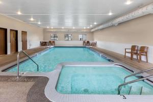 - une grande piscine dans un bâtiment avec des chaises dans l'établissement Super 8 by Wyndham St. Ignace, à Saint-Ignace