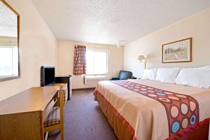 una camera d'albergo con un grande letto e una scrivania di Super 8 by Wyndham Plano/Dallas Area a Plano