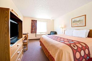 a hotel room with a bed and a flat screen tv at Super 8 by Wyndham Plano/Dallas Area in Plano