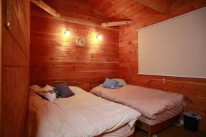 two beds in a room with wooden walls at Stay in Toya in Lake Toya