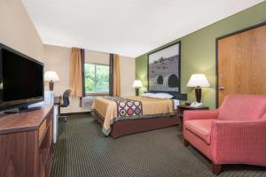 a hotel room with a bed and a flat screen tv at Super 8 by Wyndham Olney in Olney
