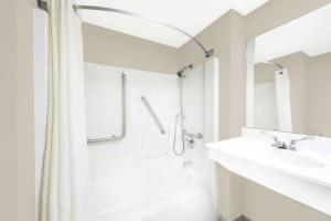 a white bathroom with a shower and a sink at Super 8 by Wyndham Bolivar in Bolivar +22 photos