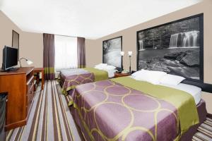 a hotel room with two beds and a flat screen tv at Super 8 by Wyndham Bolivar in Bolivar