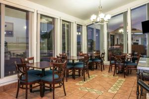 una sala da pranzo con tavoli, sedie e finestre di Super 8 by Wyndham San Marcos a San Marcos