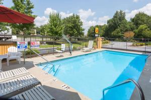 a large swimming pool with chairs and an umbrella at Super 8 by Wyndham Norcross/I-85 Atlanta in Norcross