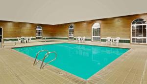 a swimming pool in a building with chairs and a building at Super 8 by Wyndham Battle Mountain in Battle Mountain