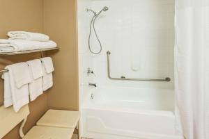 a bathroom with a tub and a shower with towels at Super 8 by Wyndham Calgary/Airport in Calgary