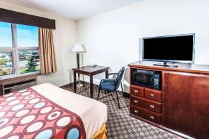 a hotel room with a bed and a flat screen tv at Super 8 by Wyndham Calgary/Airport in Calgary