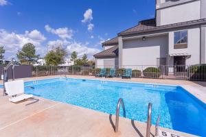- une piscine avec des chaises et une maison dans l'établissement Super 8 by Wyndham Greer/Spartanburg Area, à Greer