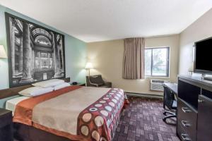 a hotel room with a bed and a desk and a television at Super 8 by Wyndham Luverne in Luverne