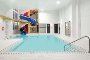 a large swimming pool with a slide in a building at Super 8 by Wyndham Grande Prairie in Grande Prairie
