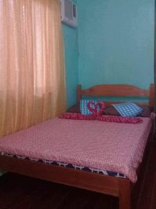 1 dormitorio con 1 cama con edredón rosa en 3Kid's Homestay Green, en General Luna
