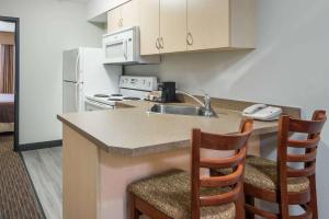 a kitchen with a sink and a counter with two chairs at Super 8 by Wyndham Grande Prairie in Grande Prairie