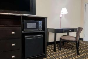 a hotel room with a desk with a microwave and a television at Super 8 by Wyndham Lithonia in Decatur
