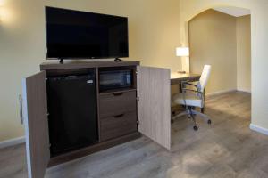 a desk with a television and a chair in a room at Days Inn by Wyndham Airport - Phoenix in Phoenix