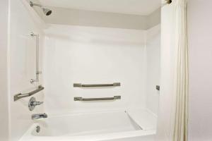 a bathroom with a shower and a white tub at Super 8 by Wyndham Gainesville in Gainesville +22 photos