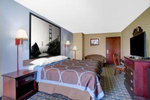 um quarto de hotel com uma cama e uma televisão em Super 8 by Wyndham Booneville em Booneville