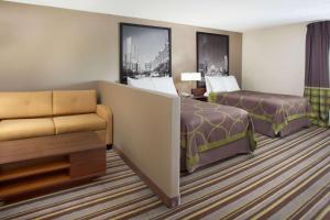 a hotel room with two beds and a couch at Super 8 by Wyndham Chicago/Rosemont/O'Hare/SE in River Grove