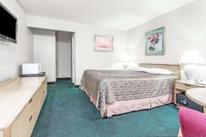 a hotel room with a bed and a flat screen tv at Travelodge by Wyndham La Grande in La Grande