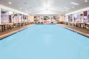 a large swimming pool with tables and chairs at Super 8 Beachfront by Wyndham Mackinaw City, MI in Mackinaw City