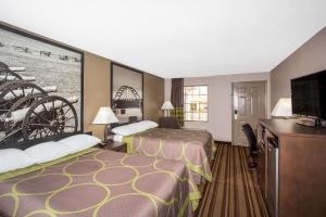 a hotel room with two beds and a flat screen tv at Super 8 by Wyndham Springdale AR in Springdale