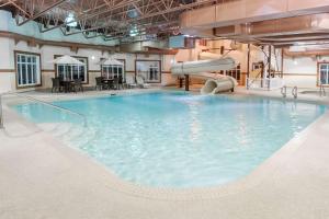 a large swimming pool with a slide in a building at Ramada by Wyndham Drumheller Hotel & Suites in Drumheller