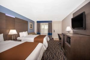 a hotel room with two beds and a flat screen tv at Travelodge Inn & Suites by Wyndham Anaheim on Disneyland Dr in Anaheim