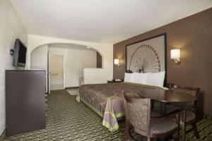 ein Hotelzimmer mit einem Bett und einem Tisch in der Unterkunft Super 8 by Wyndham Grand Prairie Southwest in Grand Prairie