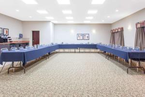 Una sala de conferencias con mesas y sillas azules. en Ramada by Wyndham Pincher Creek, en Pincher Creek