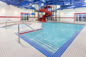 a swimming pool with a slide in a building at Ramada by Wyndham Pincher Creek in Pincher Creek