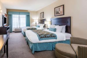a hotel room with a bed, chair, and a television at Wingate by Wyndham New Braunfels in New Braunfels