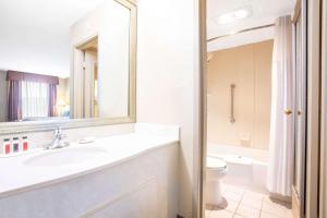 a bathroom with a sink and a toilet and a mirror at Baymont by Wyndham Hays in Hays