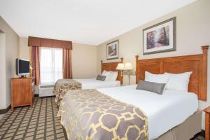 a hotel room with two beds and a flat screen tv at Baymont by Wyndham Hays in Hays