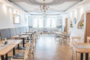 a restaurant with tables and chairs and a chandelier at Landhotel Stegersbach in Stegersbach