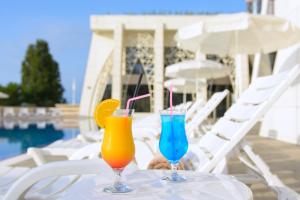two cocktails sitting on a table next to a pool at The Grand Gloria Hotel in Batumi