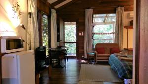 ein Wohnzimmer mit einem Sofa, einem TV und einem Tisch in der Unterkunft Black Cockatoo Lodge in Nannup