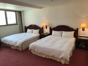 ein Hotelzimmer mit 2 Betten und 2 Fenstern in der Unterkunft Sunrise Hotel in Tainan
