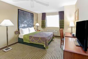 a hotel room with a bed and a flat screen tv at Super 8 by Wyndham Gurnee in Gurnee +6 photos