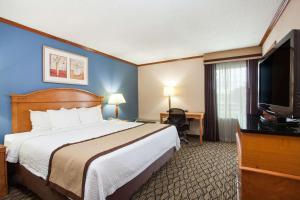 a hotel room with a bed and a flat screen tv at Baymont by Wyndham Madison Heights Detroit Area in Madison Heights