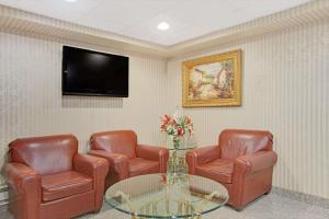 Sala de espera con 2 sillas, mesa y TV en Travelodge by Wyndham Parsippany, en Parsippany