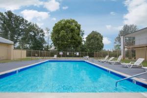 a swimming pool with lounge chairs and a house at Super 8 by Wyndham Brinkley in Brinkley
