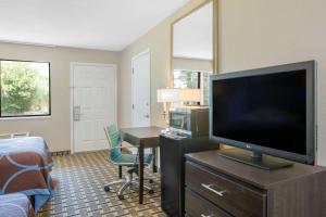 a hotel room with a flat screen tv and a desk at Super 8 by Wyndham Brinkley in Brinkley