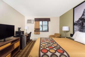 a hotel room with a bed and a flat screen tv at Super 8 by Wyndham Eau Claire I-94 in Eau Claire