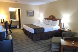 a hotel room with a large bed and a living room at Baymont by Wyndham Lynchburg in Lynchburg