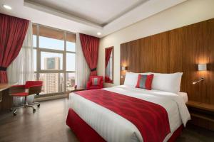 Ramada Encore by Wyndham Kuwait Downtown في الكويت: غرفة فندقية بسرير كبير ونافذة