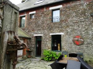 een bakstenen gebouw met een houten tafel ervoor bij Le Relais in Saint-Sauveur-la-Pommeraye