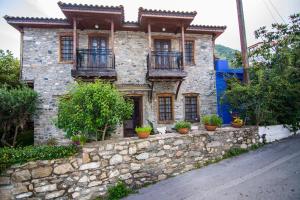 an old stone house with potted plants on a stone wall at Dreaming House in Nea Vrasna