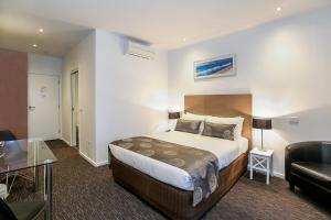Habitación de hotel con cama y sofá en Belmercer Motel, en Geelong