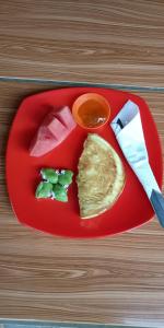 a red plate of food with meat and vegetables on a table at Kubu Sari Guest House in Pemuteran